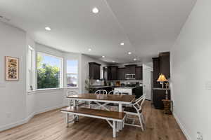 Dining space featuring light wood-style flooring, recessed lighting, and a textured ceiling