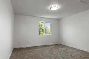 Empty room featuring dark carpet and a textured ceiling