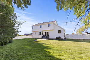 Rear view of house featuring a fenced backyard, entry steps, stucco siding, and a gate