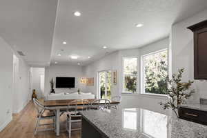 Kitchen featuring light stone countertops, recessed lighting, a textured ceiling, dark wood finish cabinetry, and open floor plan