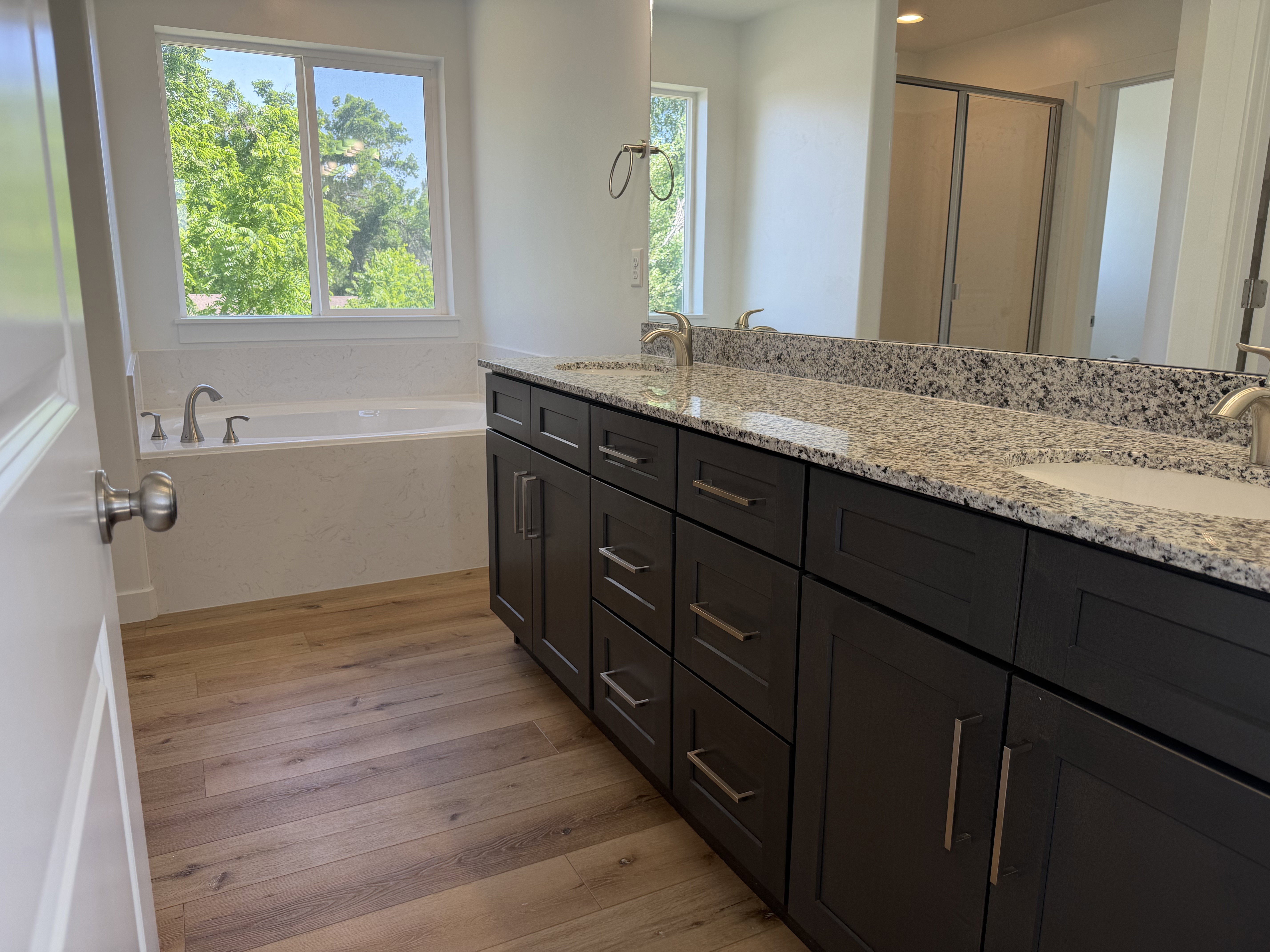Bathroom featuring a dual vanity with dark wood cabinetry, light-toned stone countertop, and two integrated sinks