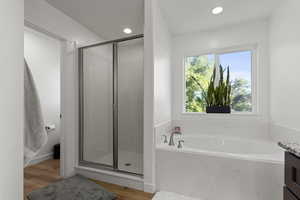 Bathroom featuring a bath, a shower stall, vanity, light wood-style floors, and recessed lighting
