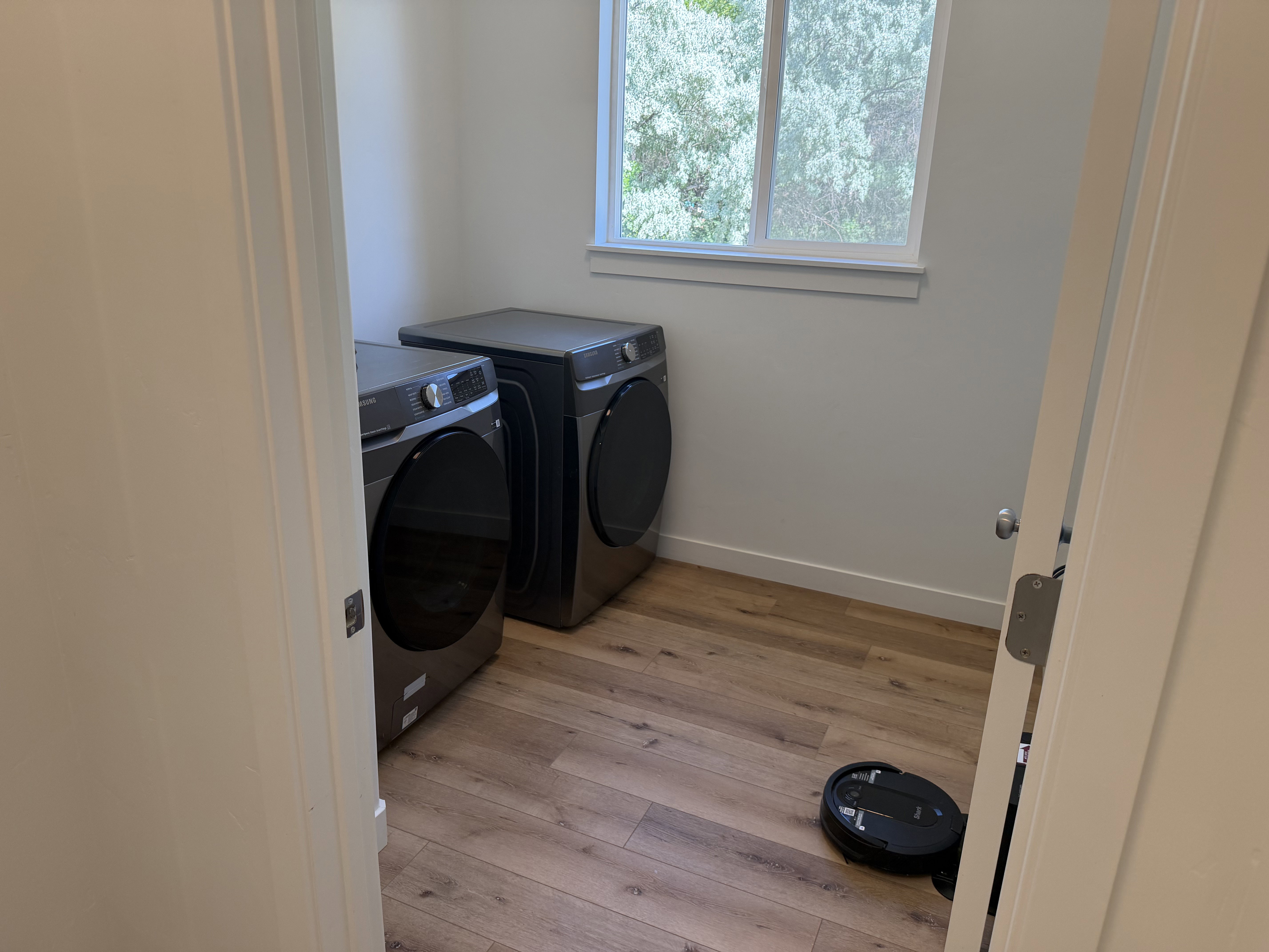 Dedicated laundry space featuring wood-finish flooring and a single window