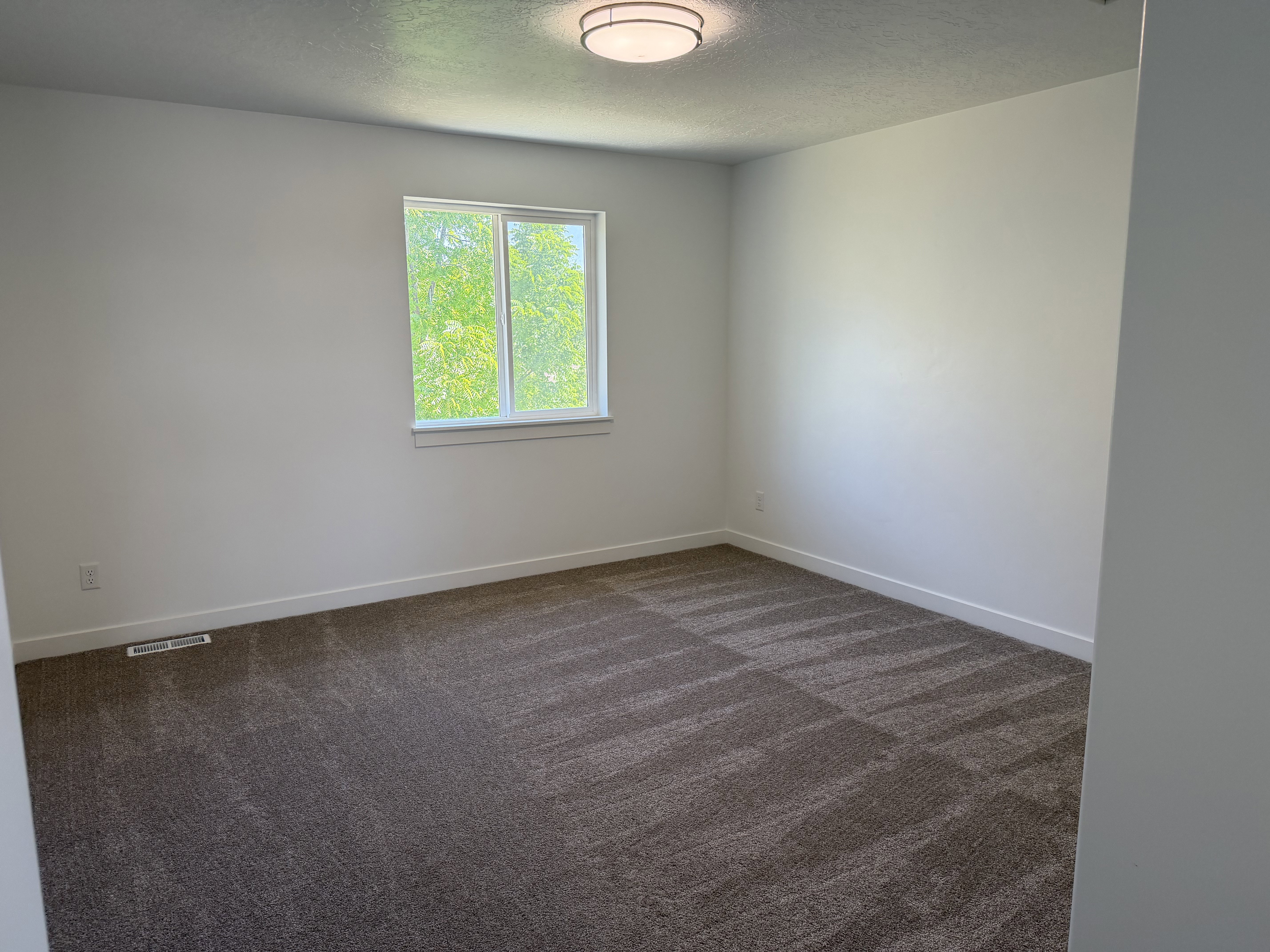 Spacious room featuring neutral paint, patterned carpet, a single window, white trim, and a flush mount ceiling light