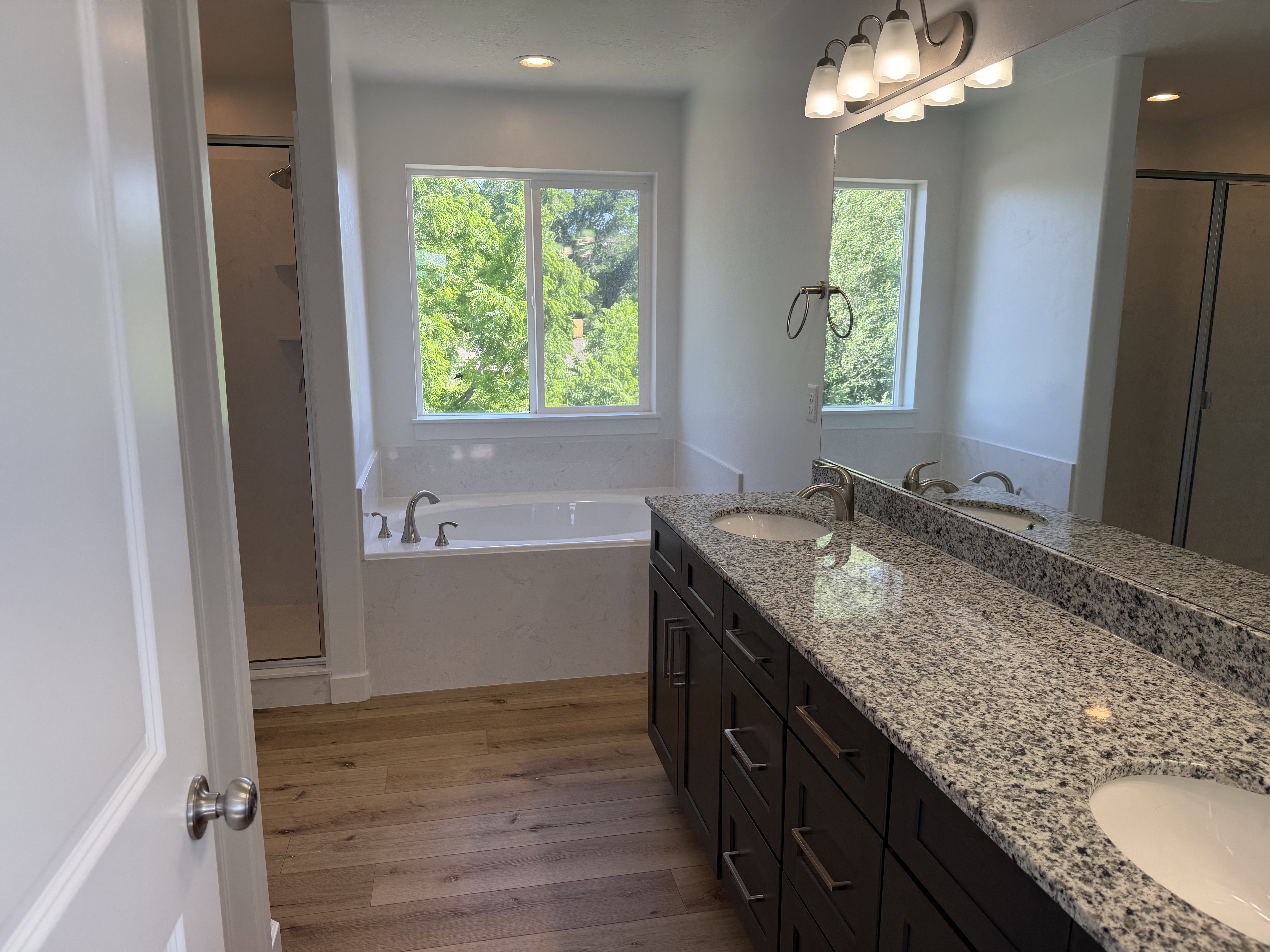 Expansive vanity featuring dual undermount sinks, granite countertop, and dark wood-finish cabinetry