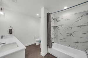 Full bath with double vanity, shower / tub combo, recessed lighting, and finished concrete floors