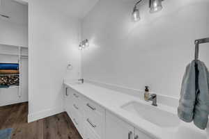 Full bath featuring double vanity, dark wood-style flooring, and a walk in closet
