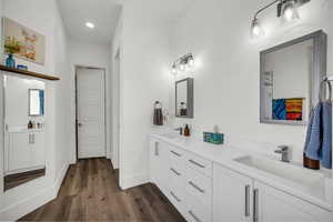 Full bathroom featuring double vanity, dark wood-type flooring, and recessed lighting