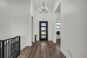 Foyer entrance featuring dark wood finished floors, a chandelier, washer / dryer, and a high ceiling
