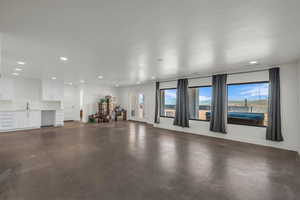 Unfurnished living room featuring recessed lighting and concrete floors
