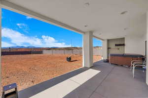 Fenced backyard with a patio, a hot tub, and a mountain view