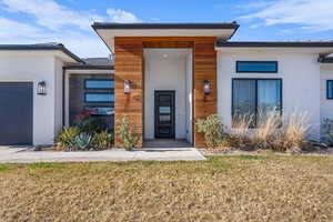 Property entrance featuring a yard, a garage, and stucco siding