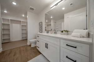 Full bathroom with a shower with curtain, a walk in closet, light wood-type flooring, vanity, and recessed lighting