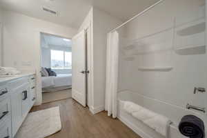 Ensuite bathroom featuring vanity, light wood-type flooring, and shower / bath combo with shower curtain