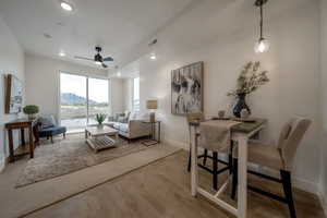 Living room with a mountain view, light wood-style flooring, ceiling fan, and recessed lighting