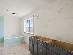 Full bath with a bath, light wood-style flooring, vanity, and a textured ceiling
