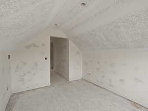 Additional living space featuring baseboards and a textured ceiling