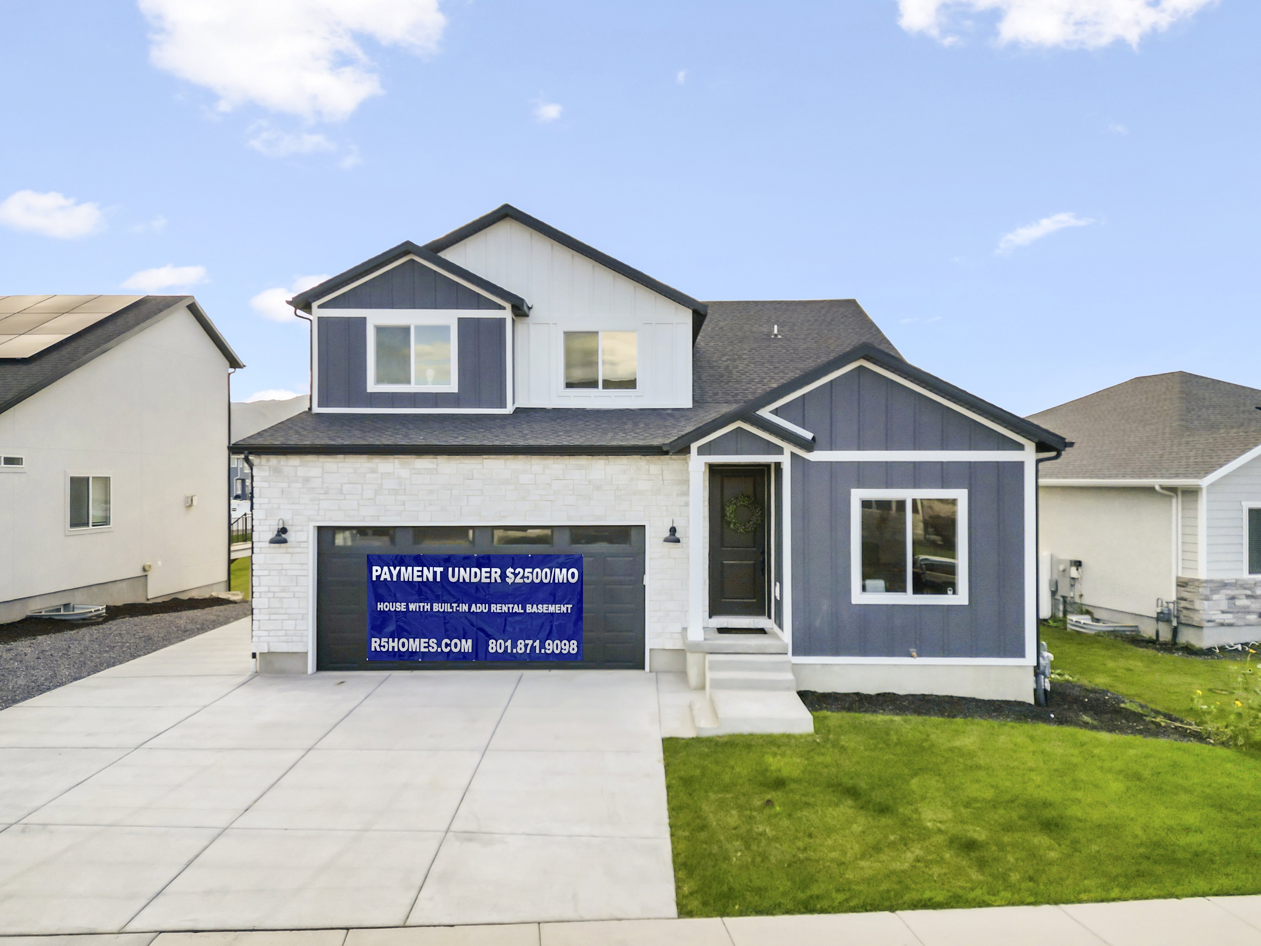 View of front of property featuring a front yard, board and batten siding, a garage, concrete driveway, and a shingled roof