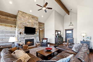 Living area featuring wood finished floors, a stone fireplace, and a ceiling fan