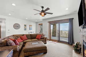 Living area featuring light carpet, a glass covered fireplace, recessed lighting, and ceiling fan
