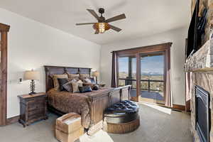 Bedroom with carpet, a ceiling fan, access to exterior, and a glass covered fireplace