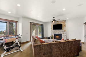 Carpeted living room featuring a barn door, a stone fireplace, ceiling fan, and recessed lighting