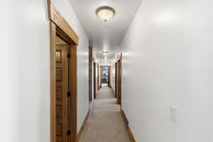 Hallway featuring light carpet and baseboards