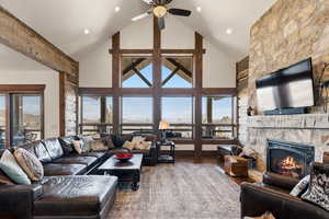 Living room with wood finished floors, a fireplace, a high ceiling, and ceiling fan