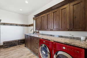 Laundry area with light wood finished floors, cabinet space, washing machine and clothes dryer, and recessed lighting