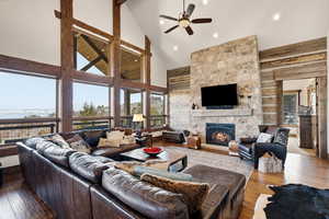 Living room featuring wood-type flooring, a stone fireplace, lofted ceiling, ceiling fan, and recessed lighting