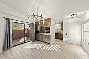 Kitchen with light countertops, plenty of natural light, wood finish floors, a chandelier, and lofted ceiling