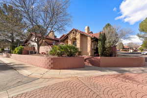 View of side of property with a tile roof, stucco siding, and a chimney