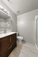 Bathroom featuring vanity, a textured wall, wood tiled floors, a shower stall, and a textured ceiling