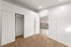 Unfurnished bedroom featuring a closet, light carpet, and recessed lighting