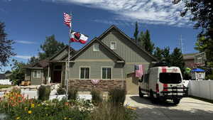 View of front of home featuring board and batten siding, stone siding, and concrete driveway