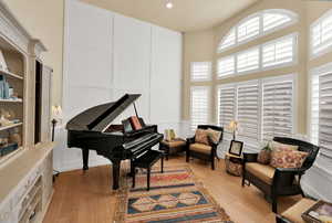Living area featuring a decorative wall, light wood finished floors, a high ceiling, plenty of natural light, and recessed lighting