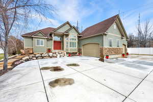 Craftsman-style house with stone siding, concrete driveway, a shingled roof, a garage, and board and batten siding