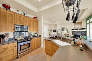 Kitchen featuring stainless steel appliances, open floor plan, a fireplace, light wood-type flooring, and light wood finish cabinetry
