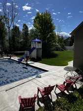 View of pool with a yard, a playground, and patio surround