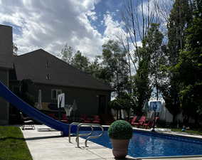 View of swimming pool featuring a water slide and patio surround