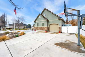 View of side of home featuring a gate, driveway, stone siding, board and batten siding, and an attached garage