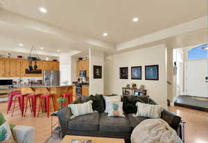 Living room with light wood-style flooring and recessed lighting
