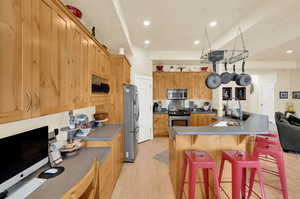 Kitchen featuring a breakfast bar, stainless steel appliances, light wood-style flooring, recessed lighting, and a kitchen island