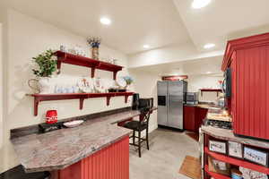 Kitchen with open shelves, a peninsula, stainless steel appliances, concrete floors, and recessed lighting