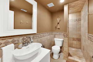 Full bathroom featuring tile walls, a walk in shower, wainscoting, vanity, and recessed lighting