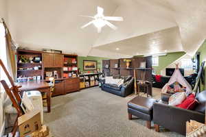 Living area featuring light colored carpet, a ceiling fan, and a high ceiling
