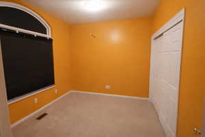 Unfurnished bedroom with light colored carpet and a closet