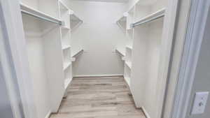 Walk in closet with light wood-style floors