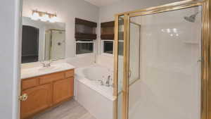 Full bath featuring a shower stall, vanity, a whirlpool tub, and light wood finished floors