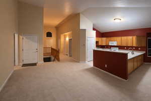 Kitchen with light countertops, white appliances, light carpet, vaulted ceiling, and wood finish cabinetry